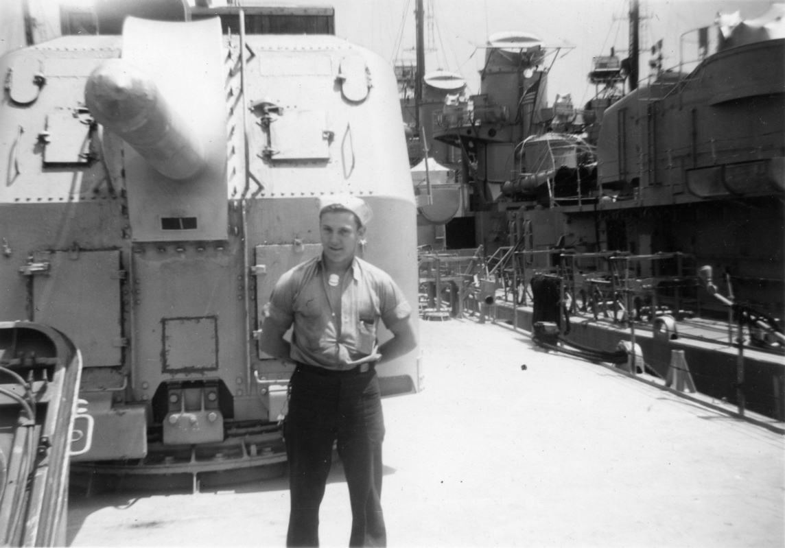 [unknown]<br>Standing in front of a capped 5&rdquo; gun.<br>Note that the stacks of the adjacent destroyer are also capped.